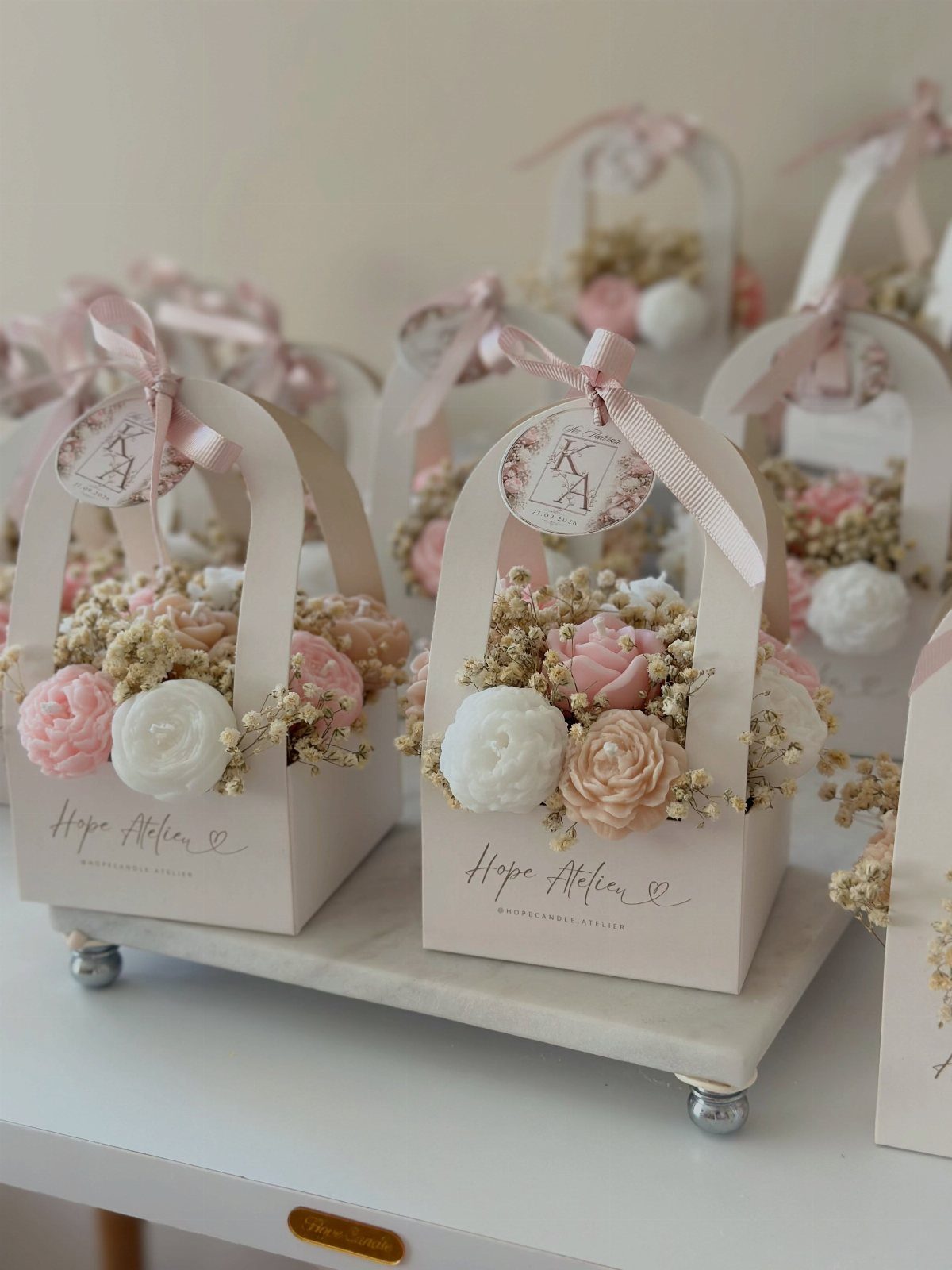 Small white gift baskets filled with dried pink and white flowers on marble tray