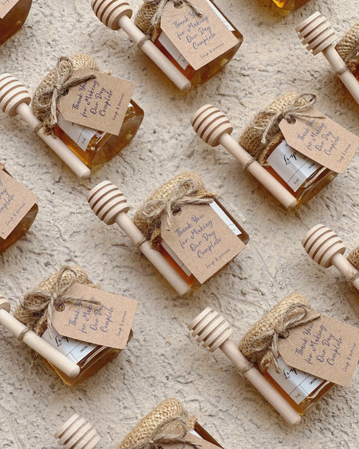 Mini honey jars with burlap toppers, wooden dippers, and white gift tags.